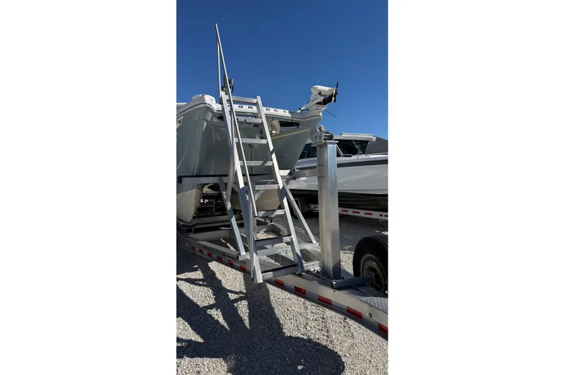 Slide: The Image of 2023 World Cat 280 DC-X boat on trailer with ladder under clear blue sky. - 26