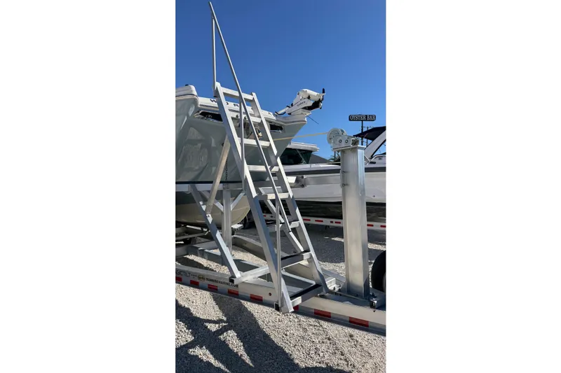 Slide: The Image of Aluminum ladder on a 2023 World Cat 280 DC-X boat trailer under clear blue sky. - 27