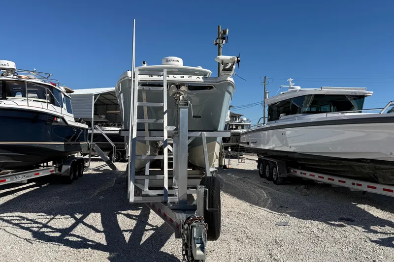 Slide: The Image of 2023 World Cat 280 DC-X boat on trailer, flanked by other boats, under clear blue sky. - 32