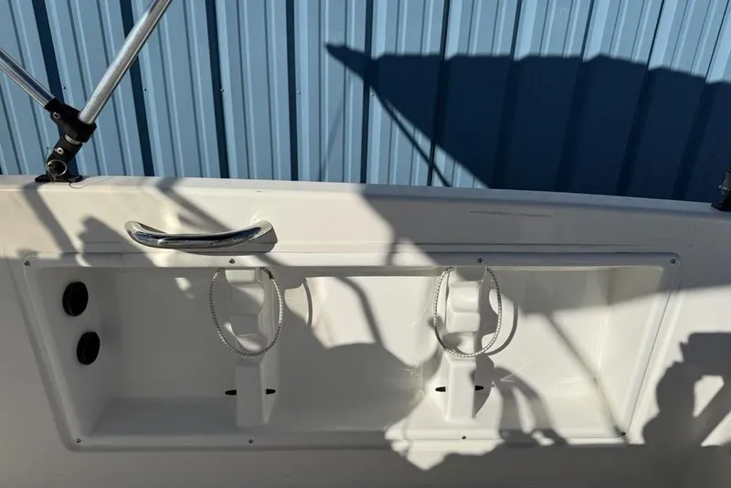 Slide: The Image of 2019 Bayliner Element E18 boat interior with rod holders and blue metal siding background. - 24