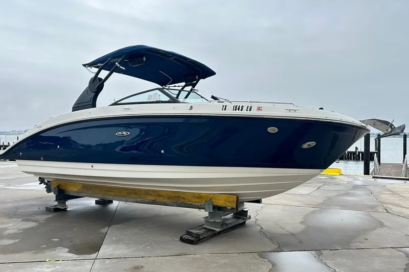 Slide: The Image of 2018 Sea Ray SDX 270 boat on dock, blue and white exterior, overcast sky. - 39