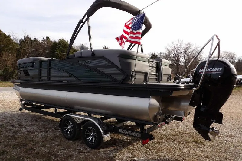 Slide: The Image of 2026 Bennington M Quad Bench 22 MFB pontoon boat on trailer with American flag. - 3