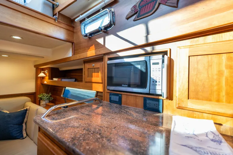 Slide: The Image of 2013 Sabre 38 Salon Express interior with microwave, wooden cabinetry, and cozy seating area. - 30