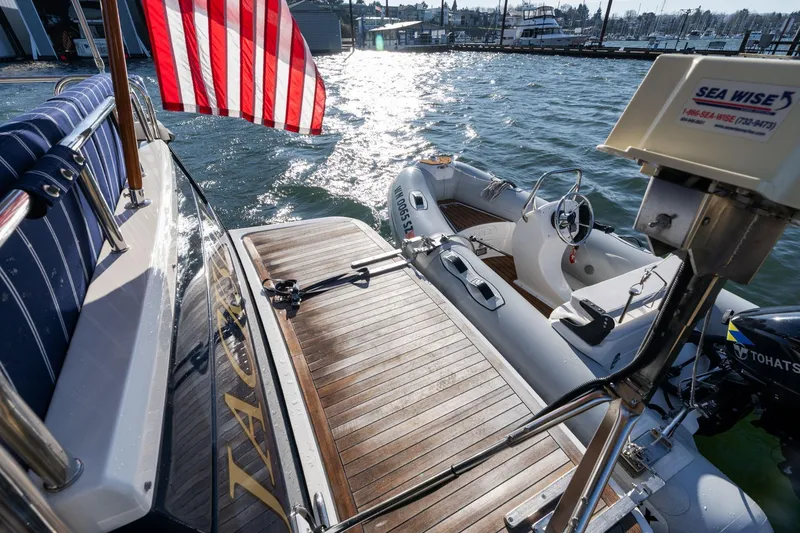Slide: The Image of 2013 Sabre 38 Salon Express yacht with American flag and attached dinghy on water. - 61