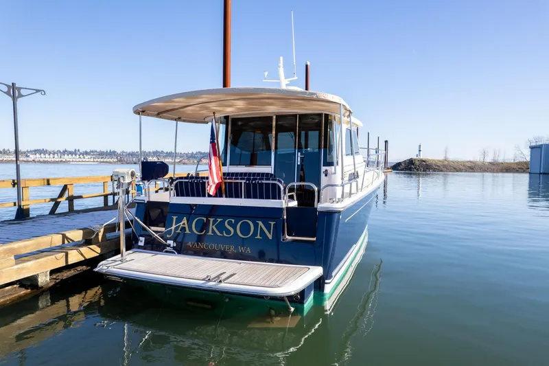 Slide: The Image of 2013 Sabre 38 Salon Express docked, rear view with "Jackson" name, calm water, clear sky. - 64