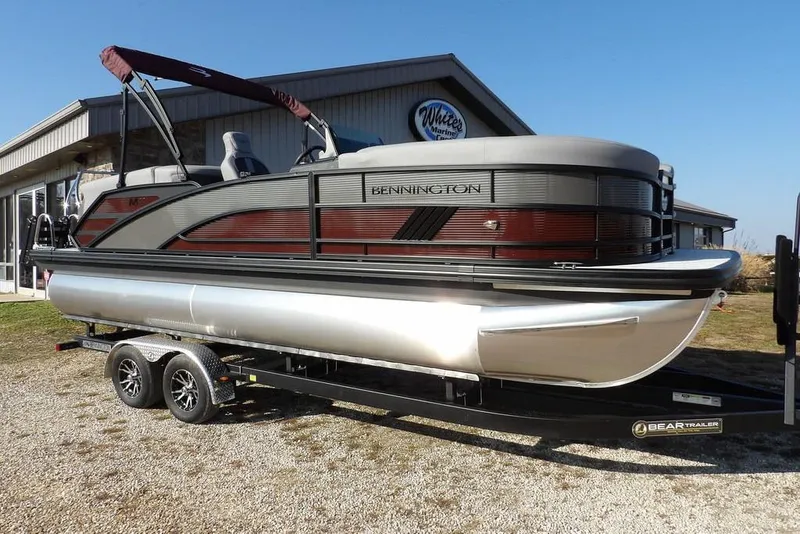 The Image of 2026 Bennington M Quad Bench 22 MFB pontoon boat on trailer, parked outdoors. - 1