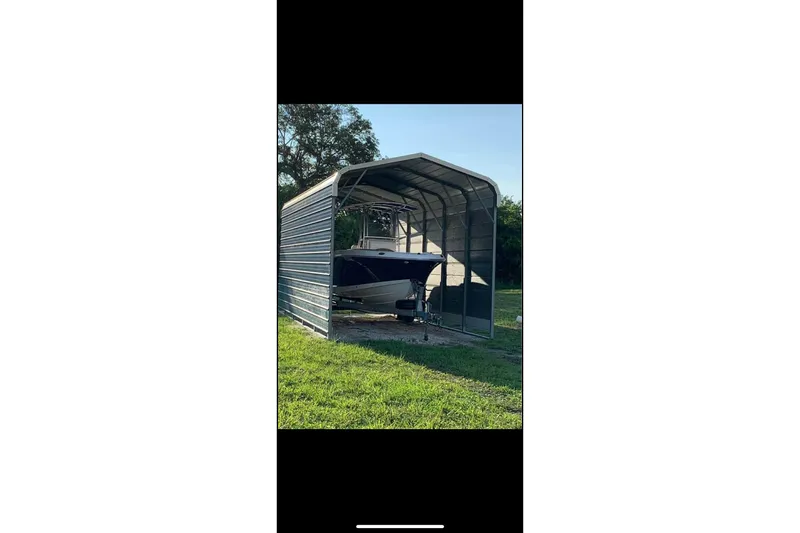 Slide: The Image of 2017 Robalo R200ES boat stored in a metal shelter on grass. - 12