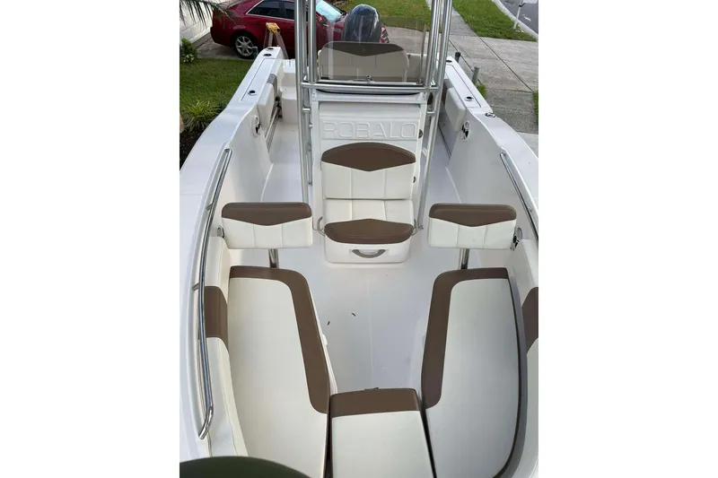 Slide: The Image of 2017 Robalo R200ES boat interior with white and brown seating, parked near a red car. - 6