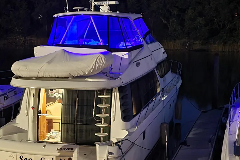 Slide: The Image of 2004 Carver 570 Voyager Pilothouse yacht docked at night with blue lighting. - 92