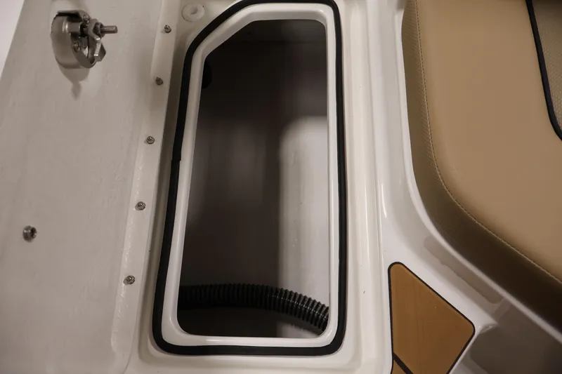 Slide: The Image of Storage compartment in 2026 Bayliner V20 boat, featuring beige seating and secure latch. - 31