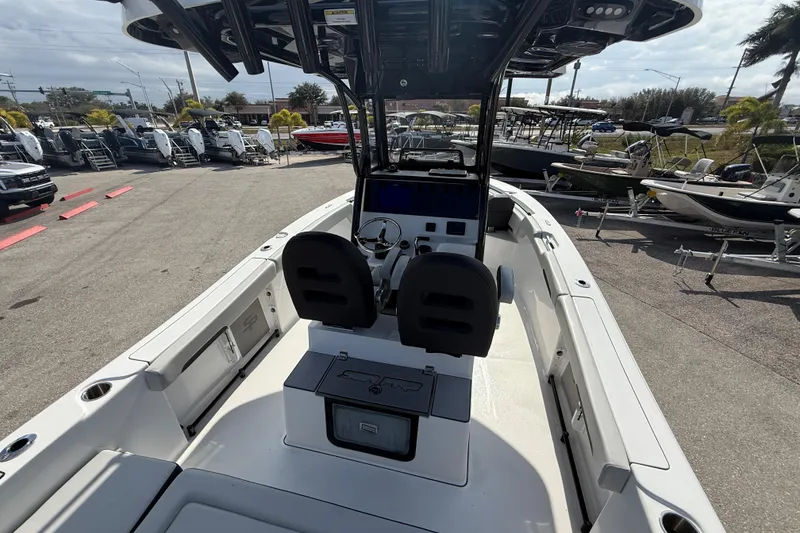Slide: The Image of 2025 Sea Pro 245FLX Sandbar boat interior with helm, seats, and console in a marina. - 13