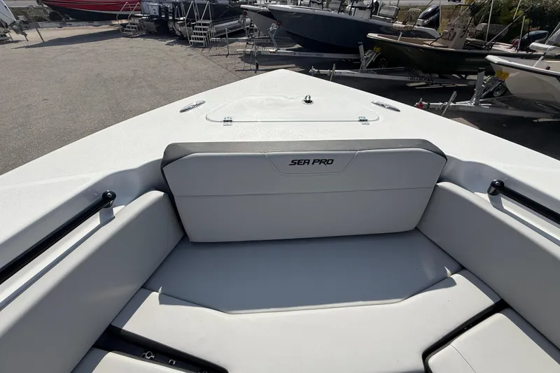 Slide: The Image of 2025 Sea Pro 245FLX Sandbar boat interior with seating and storage, docked outdoors. - 25