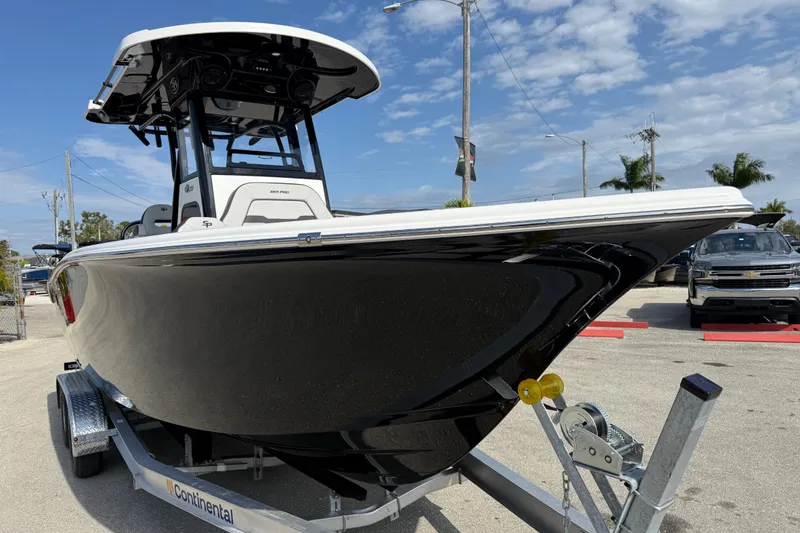 Slide: The Image of 2025 Sea Pro 245FLX Sandbar boat on trailer, sleek black hull, sunny day. - 5