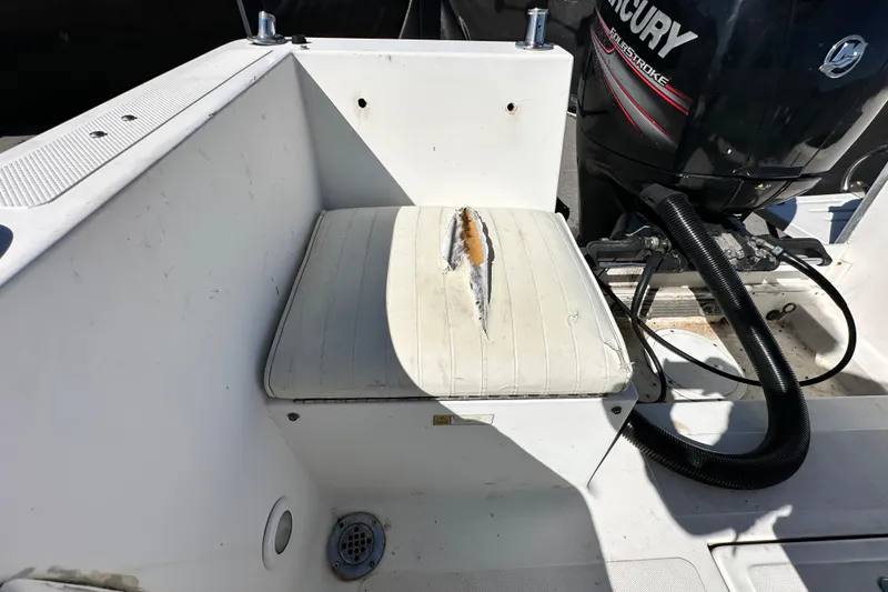 Slide: The Image of 1993 Hydra-Sports Bay Bolt 1900 boat seat with visible tear, near Mercury engine. - 58