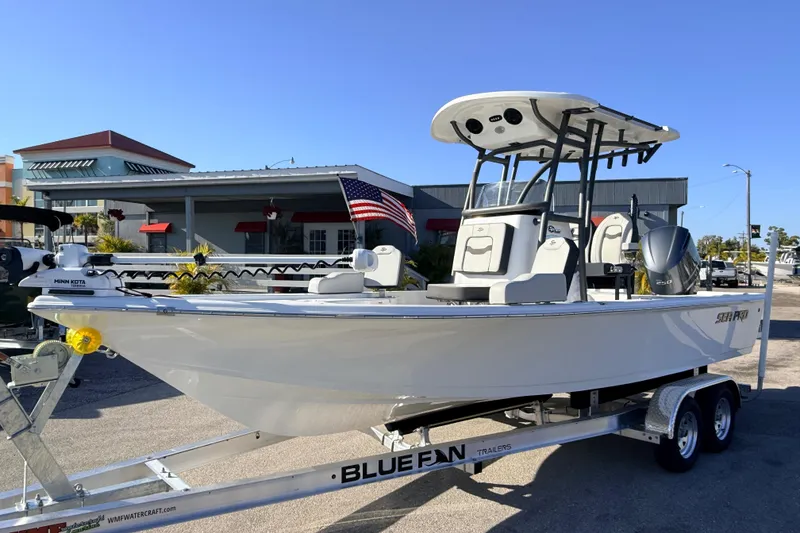The Image of 2025 Sea Pro 210 Bay boat on trailer, displayed outdoors with American flag. - 0