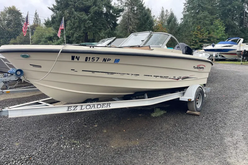 The Image of 2004 Triumph 191 Fish & Ski boat on EZ Loader trailer, parked outdoors. - 1