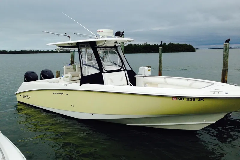 The Image of 2005 Boston Whaler 320 Outrage boat docked on calm water showing one set of isinglass - 0
