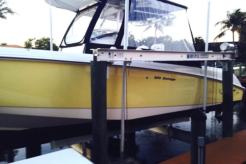 Slide: The Image of 2005 Boston Whaler 320 Outrage docked, surrounded by palm trees and clear skies. - 2