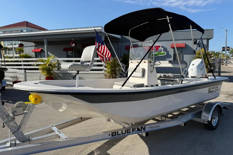 The Image of 2026 Carolina Skiff E18 JVX CC boat on trailer, with American flag and canopy. - 1