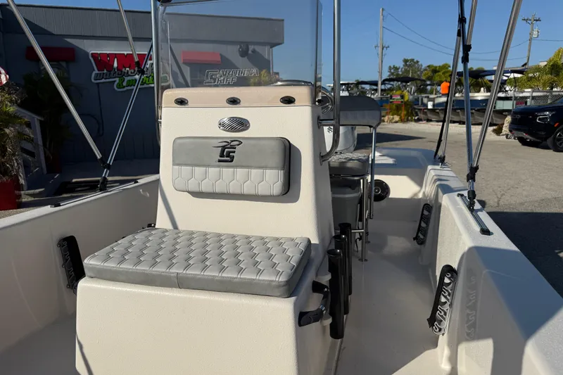 Slide: The Image of 2026 Carolina Skiff E18 JVX CC boat interior with seating and console, parked outdoors. - 13