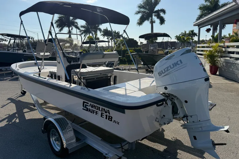 Slide: The Image of 2026 Carolina Skiff E18 JVX CC boat with Suzuki outboard motor, parked on trailer. - 7