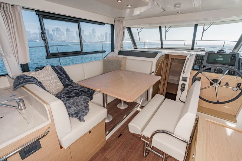 Slide: The Image of Interior of 2025 Beneteau Swift Trawler 41 with seating and helm, overlooking city skyline. - 20