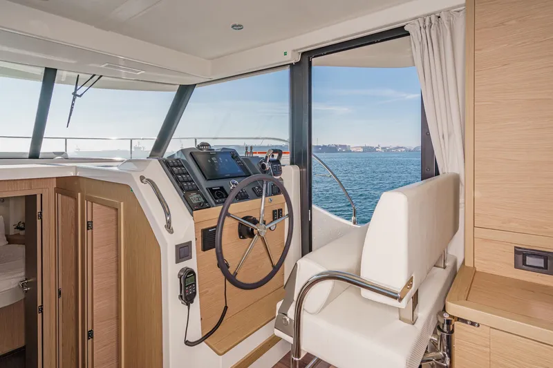 Slide: The Image of 2025 Beneteau Swift Trawler 41 helm station with ocean view and modern controls. - 21