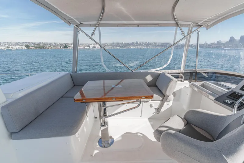 Slide: The Image of 2025 Beneteau Swift Trawler 41 interior with seating and table, overlooking scenic water view. - 45