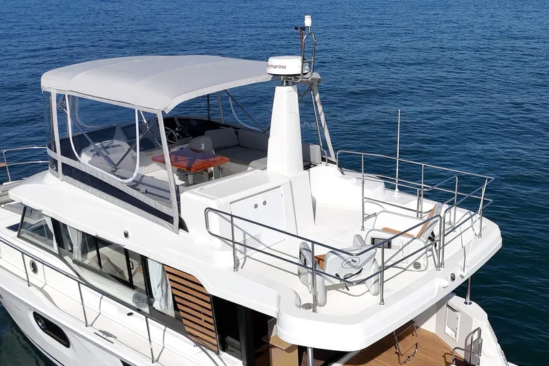 Slide: The Image of 2025 Beneteau Swift Trawler 41 on calm blue water, showcasing upper deck and seating area. - 47