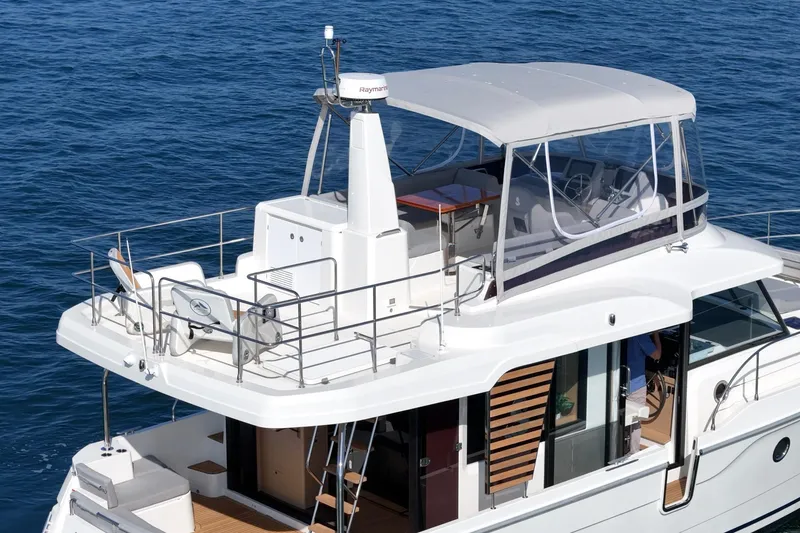Slide: The Image of 2025 Beneteau Swift Trawler 41 on calm blue water, showcasing upper deck and helm. - 48