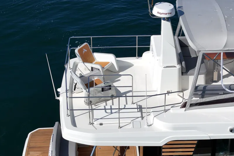 Slide: The Image of 2025 Beneteau Swift Trawler 41 flybridge with seating, overlooking calm blue water. - 49