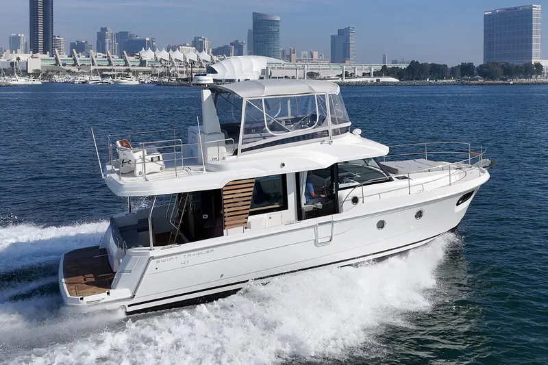 Slide: The Image of 2025 Beneteau Swift Trawler 41 cruising on water near city skyline. - 60