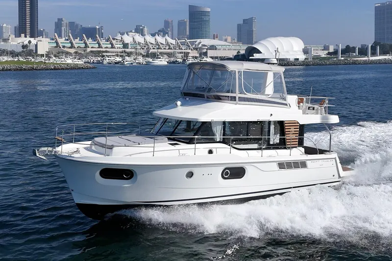 Slide: The Image of 2025 Beneteau Swift Trawler 41 cruising in a scenic urban harbor. - 61