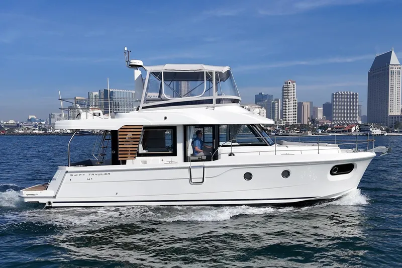 Slide: The Image of 2025 Beneteau Swift Trawler 41 cruising near city skyline on a sunny day. - 64