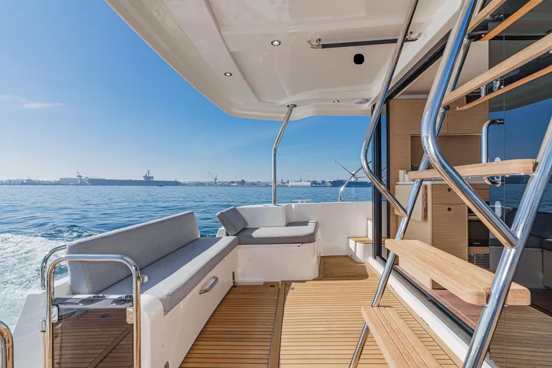 Slide: The Image of 2025 Beneteau Swift Trawler 41 deck with ocean view, featuring modern seating and wooden flooring. - 8