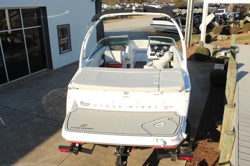 Slide: The Image of 2026 Four Winns H2 Freedom boat, rear view, parked on a trailer near a building. - 4