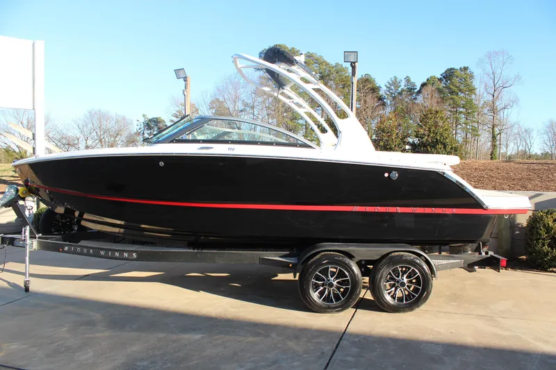 Slide: The Image of 2026 Four Winns H2 Freedom boat on trailer, black with red accents, parked outdoors. - 6