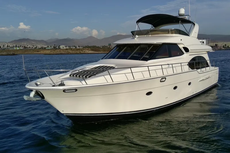 Slide: The Image of 2004 Meridian 580 Pilothouse yacht cruising on calm waters with scenic mountain backdrop. - 3