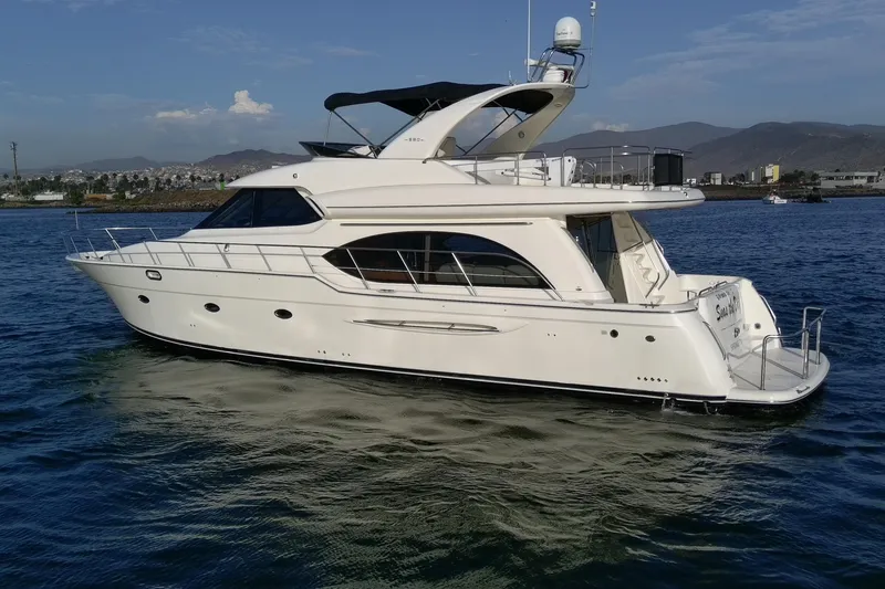 Slide: The Image of 2004 Meridian 580 Pilothouse yacht cruising on calm waters with scenic mountain backdrop. - 4