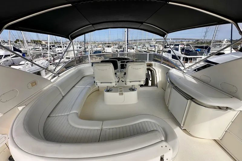 Slide: The Image of Luxurious 2004 Meridian 580 Pilothouse yacht interior with spacious seating and helm, docked at marina. - 80