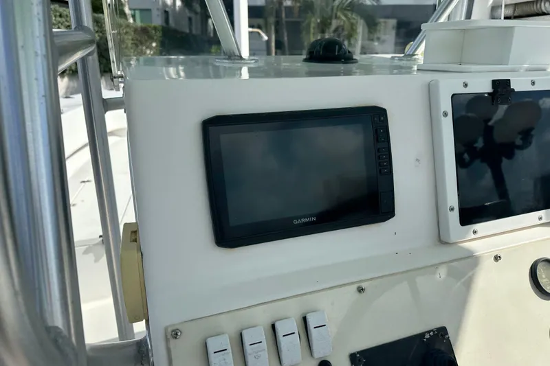 Slide: The Image of 2008 Dusky 278 Center Console boat dashboard with Garmin display and control switches. - 14