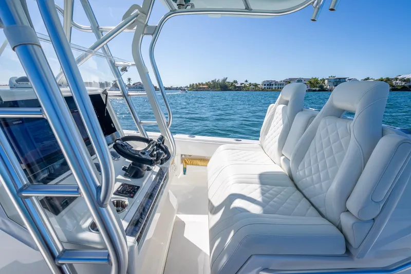Slide: The Image of 2019 SeaVee 340Z boat interior with luxurious seating and modern controls on a sunny day. - 12