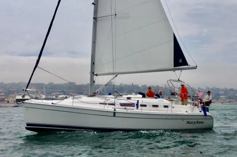 The Image of 2009 Hunter 38 sailboat on water with people onboard, sailing near coastline. - 0