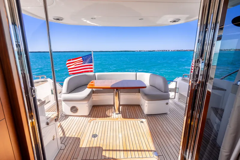 Slide: The Image of Luxurious 2018 Princess F49 yacht deck with seating, table, and American flag, overlooking blue ocean. - 46
