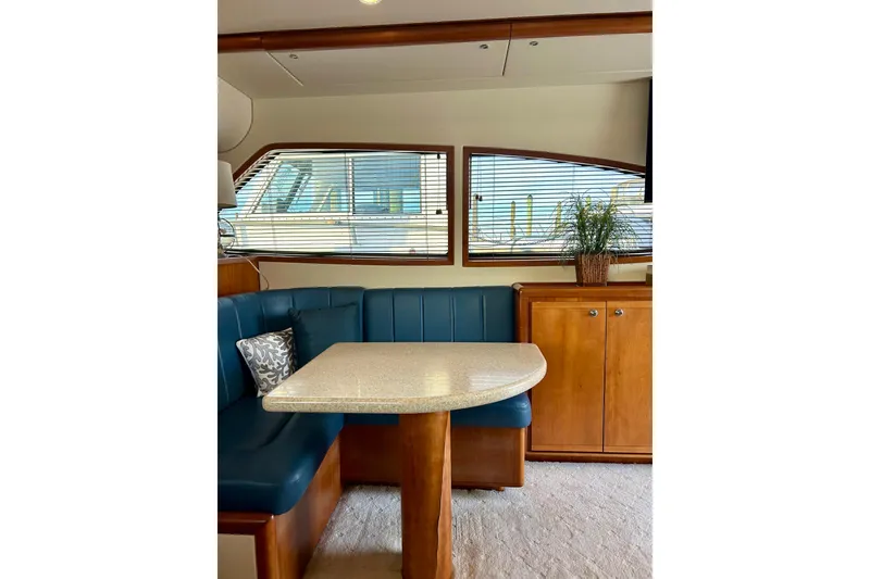 Slide: The Image of 2005 Bertram 390 Convertible yacht interior with blue seating, wooden cabinetry, and a dining table. - 38