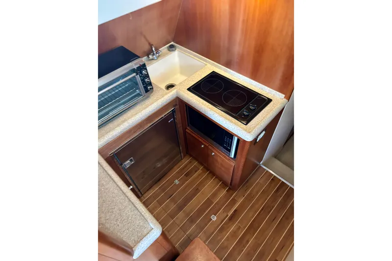 Slide: The Image of Compact kitchen in 2005 Bertram 390 Convertible yacht with stove, sink, and wooden flooring. - 48
