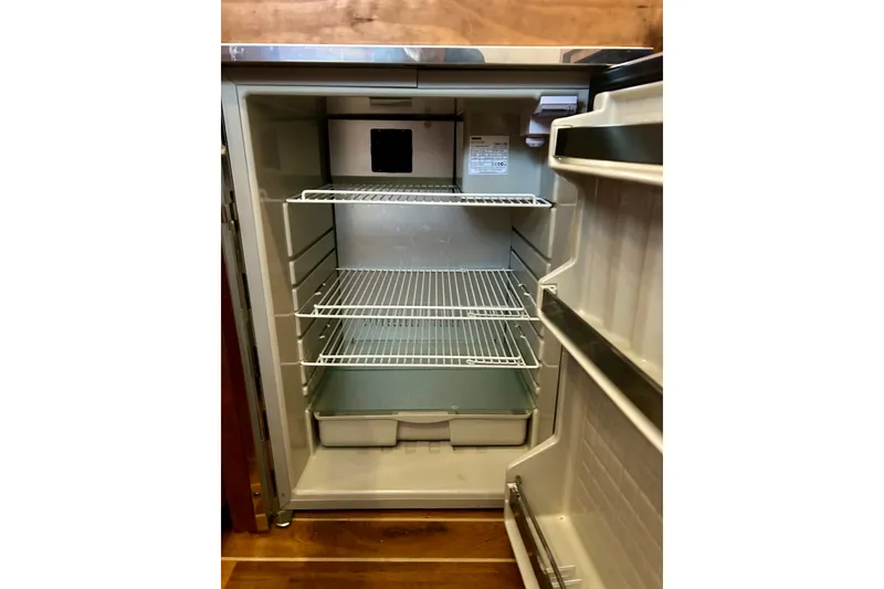 Slide: The Image of Empty refrigerator inside a 2005 Bertram 390 Convertible boat, featuring wire shelves and door storage. - 52