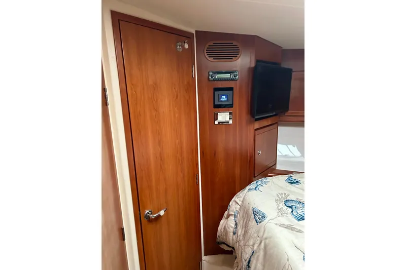 Slide: The Image of Interior of 2005 Bertram 390 Convertible with wood paneling, TV, and control panel. - 55