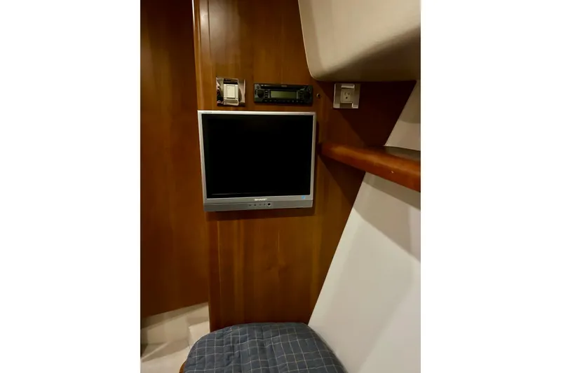 Slide: The Image of 2005 Bertram 390 Convertible interior with wall-mounted TV and wooden paneling. - 64