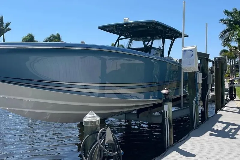 Slide: The Image of 2021 Nor-Tech 390 Sport Center Console boat docked on a lift by the water. - 10